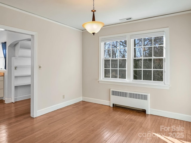 spare room featuring hardwood / wood-style flooring, ornamental molding, and radiator