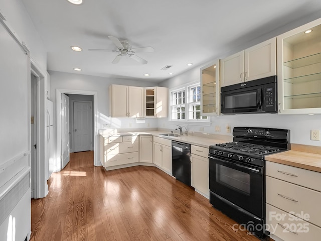 kitchen featuring sink, wooden counters, light wood-type flooring, ceiling fan, and black appliances