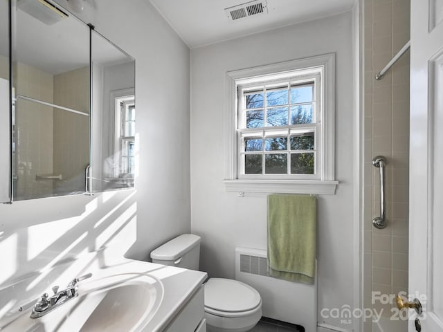 bathroom with vanity, radiator heating unit, toilet, and a tile shower