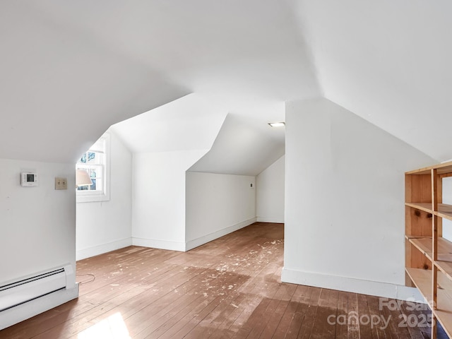 additional living space with baseboard heating, vaulted ceiling, and hardwood / wood-style flooring