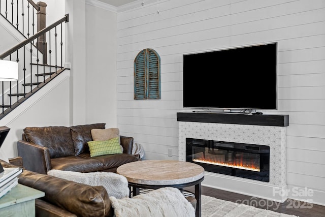 living room featuring wood walls, dark hardwood / wood-style flooring, crown molding, and a fireplace