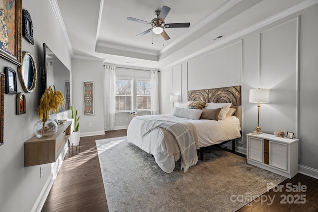 bedroom with ceiling fan, dark hardwood / wood-style flooring, crown molding, and a raised ceiling