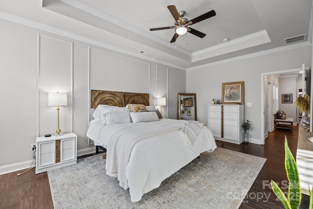 bedroom with ceiling fan, dark hardwood / wood-style floors, ornamental molding, and a raised ceiling