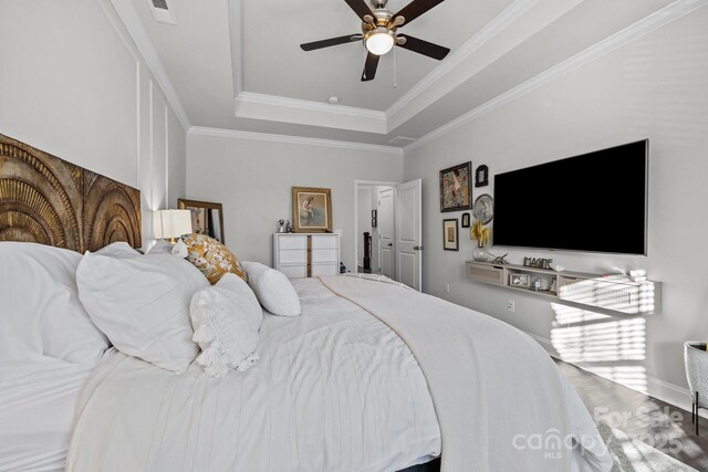 bedroom featuring ceiling fan, a tray ceiling, and ornamental molding