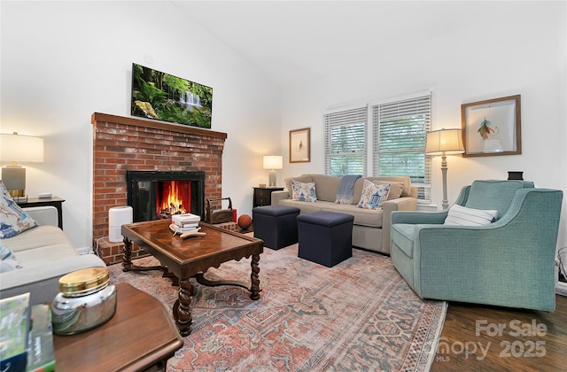 living room with vaulted ceiling, hardwood / wood-style floors, and a fireplace