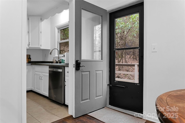 kitchen featuring sink, white cabinetry, light tile patterned floors, and dishwasher