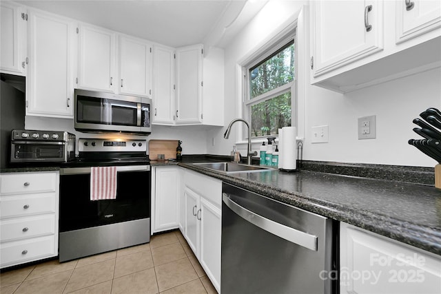 kitchen featuring sink, white cabinetry, light tile patterned floors, and appliances with stainless steel finishes