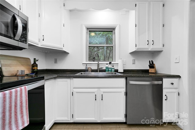 kitchen with sink, white cabinets, light tile patterned floors, and stainless steel appliances