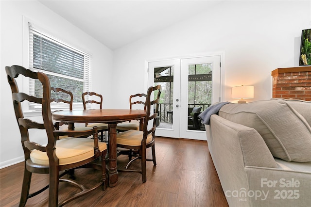 dining space with dark wood-type flooring, french doors, and vaulted ceiling