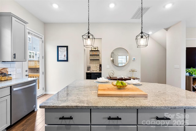 kitchen featuring light stone countertops, stainless steel dishwasher, gray cabinetry, and a kitchen island