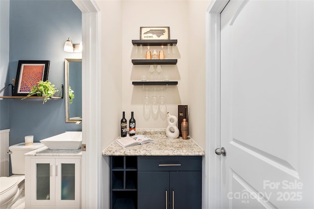 bar featuring sink and light stone countertops