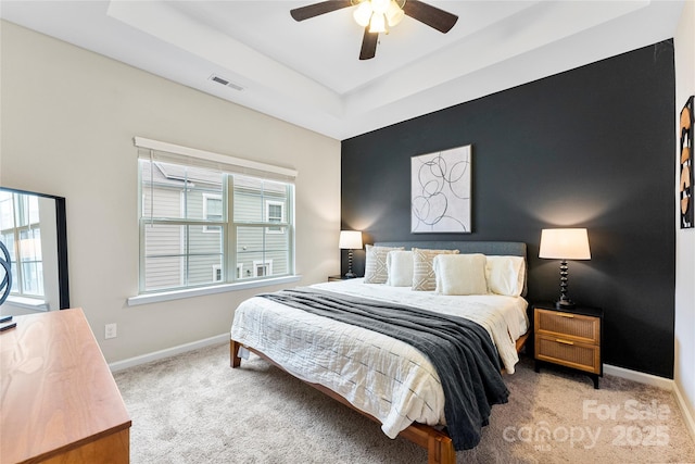 bedroom with light colored carpet, a tray ceiling, and ceiling fan