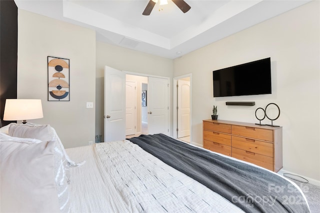 bedroom with ceiling fan and a raised ceiling