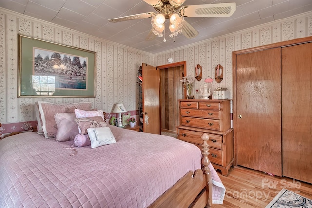 bedroom with ceiling fan, ornamental molding, a closet, and light wood-type flooring