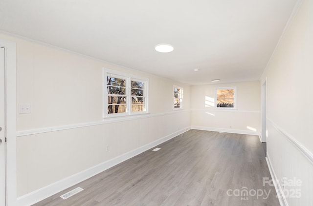 empty room featuring ornamental molding, visible vents, and wood finished floors