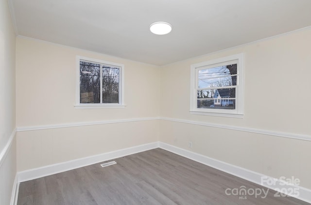 unfurnished room featuring ornamental molding, visible vents, dark wood finished floors, and baseboards