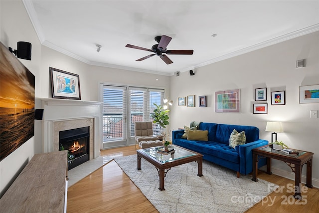 living room with a premium fireplace, ornamental molding, ceiling fan, and light hardwood / wood-style floors