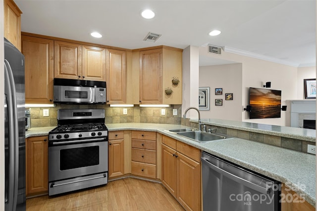 kitchen featuring appliances with stainless steel finishes, light hardwood / wood-style floors, sink, and decorative backsplash