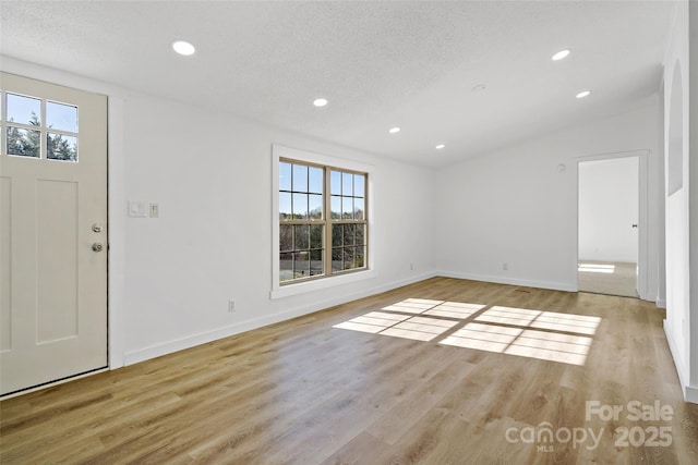 entrance foyer with a textured ceiling and light hardwood / wood-style floors