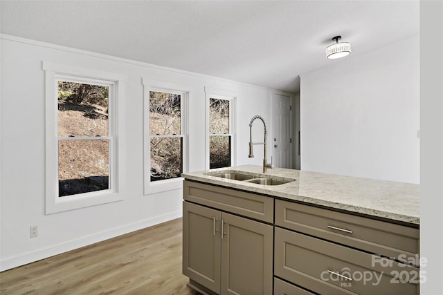 kitchen with light stone countertops, sink, gray cabinets, and light wood-type flooring