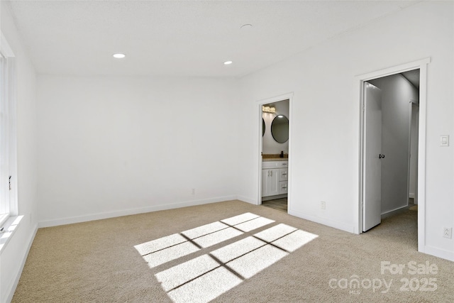 unfurnished bedroom featuring light carpet and ensuite bath