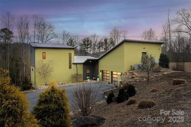 back house at dusk featuring a garage and cooling unit