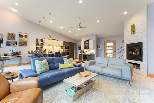 living room with ceiling fan, a stone fireplace, high vaulted ceiling, and light tile patterned floors