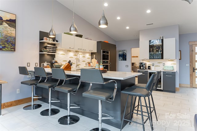 kitchen with a kitchen bar, a center island, pendant lighting, decorative backsplash, and white cabinets