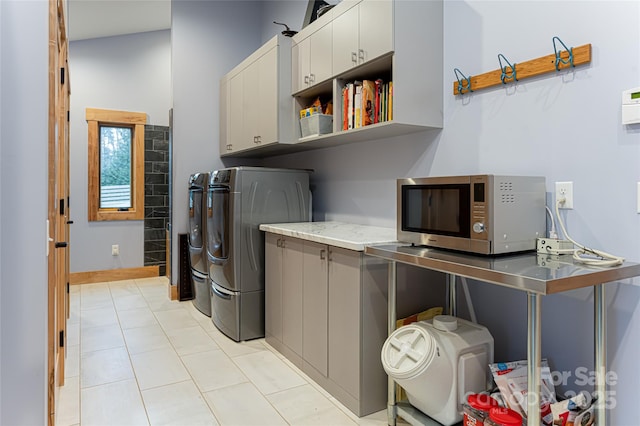 washroom with cabinets, washing machine and clothes dryer, and light tile patterned flooring