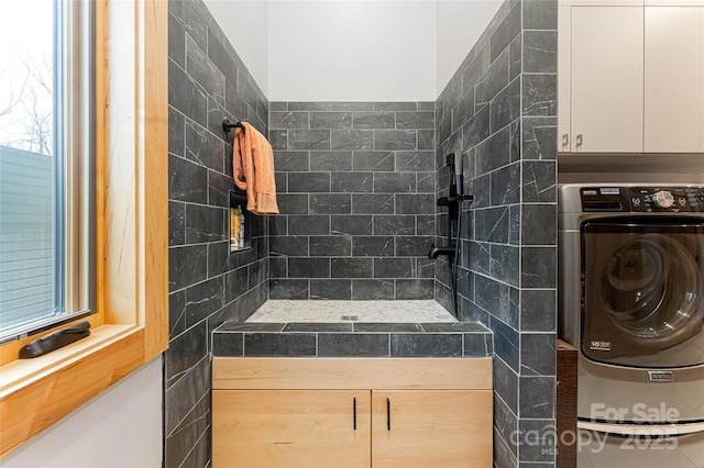 bathroom with a tile shower and washer / clothes dryer