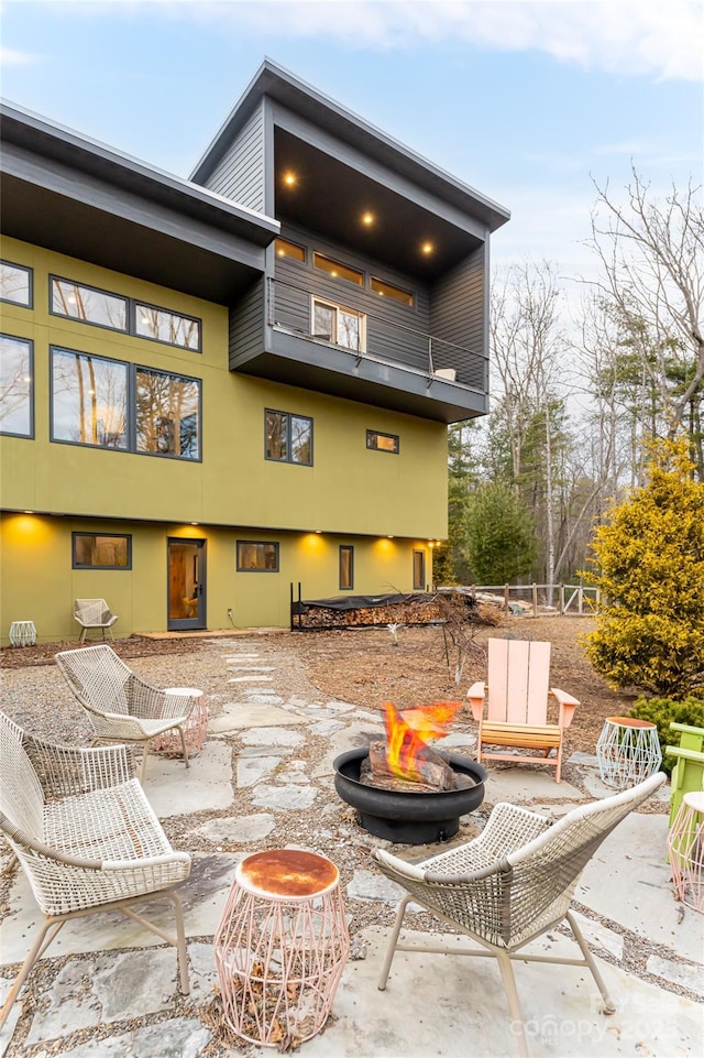 rear view of property featuring a balcony, a patio area, and an outdoor fire pit