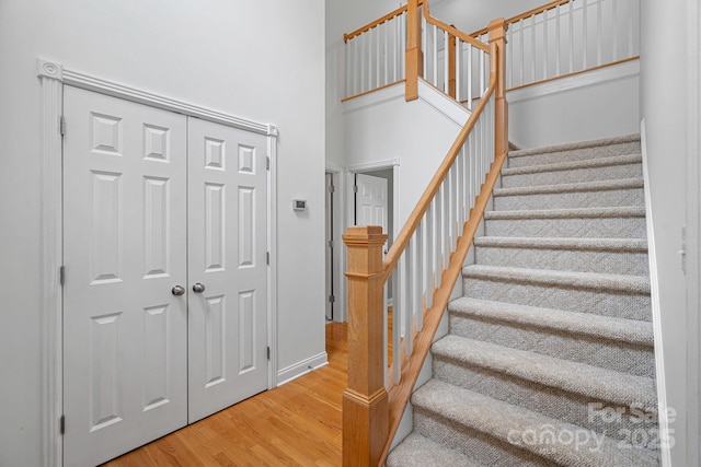 staircase with hardwood / wood-style flooring and a towering ceiling