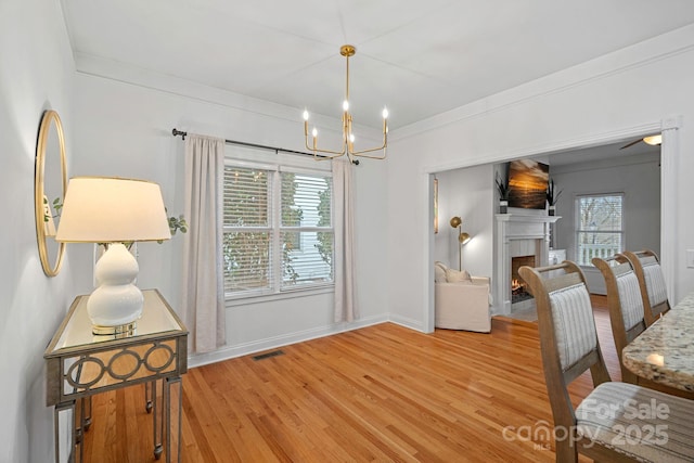 dining area featuring hardwood / wood-style flooring, a wealth of natural light, ornamental molding, and an inviting chandelier