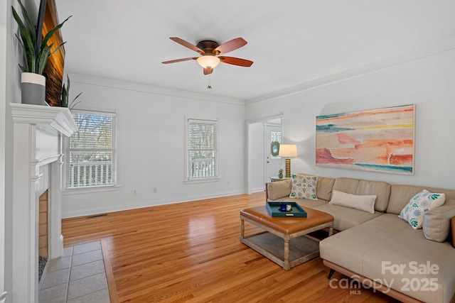 living room with ceiling fan, light wood-type flooring, and ornamental molding