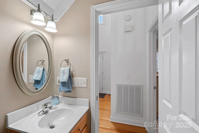 bathroom with hardwood / wood-style flooring, vanity, and crown molding