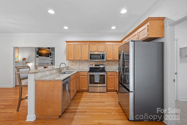 kitchen featuring light stone countertops, appliances with stainless steel finishes, a kitchen bar, sink, and backsplash