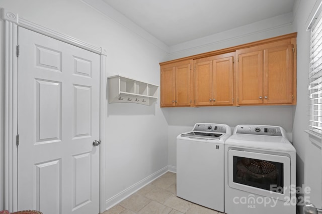 clothes washing area featuring cabinets, ornamental molding, and separate washer and dryer