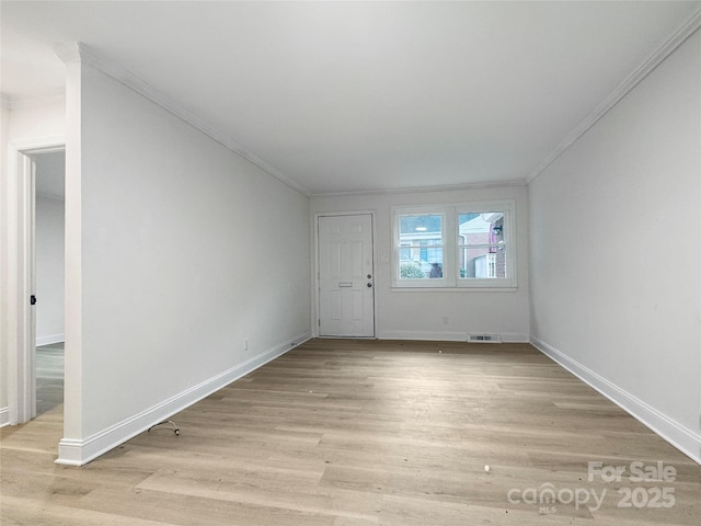 spare room with ornamental molding and light hardwood / wood-style floors