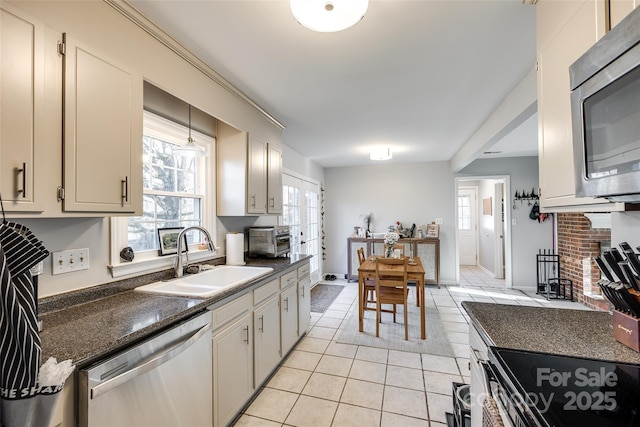 kitchen featuring appliances with stainless steel finishes, decorative light fixtures, a fireplace, sink, and light tile patterned floors