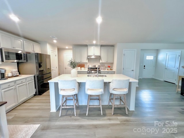 kitchen with a kitchen island with sink, a breakfast bar area, and stainless steel appliances