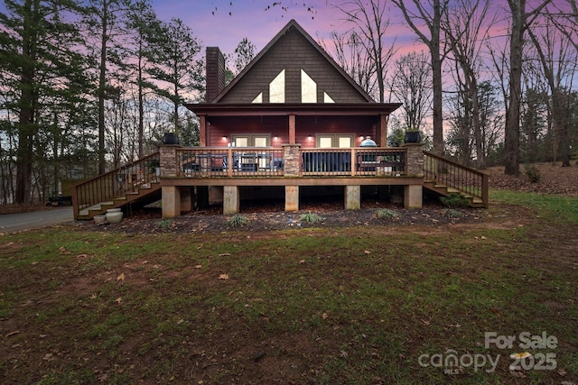 back house at dusk featuring a deck and a yard