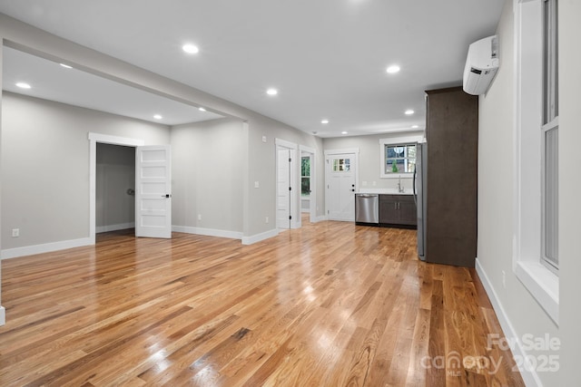 unfurnished living room with light hardwood / wood-style flooring and a wall mounted air conditioner