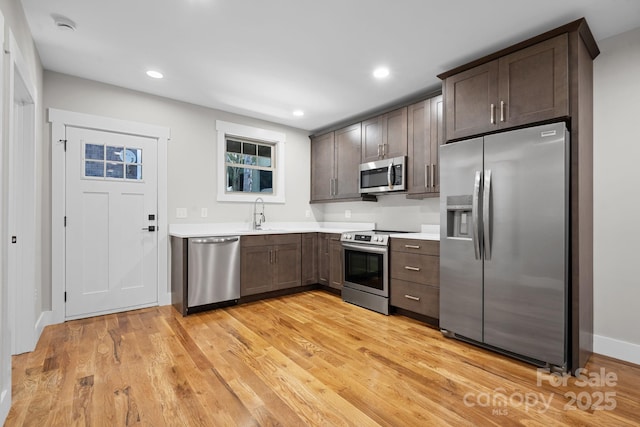 kitchen featuring sink, light hardwood / wood-style flooring, dark brown cabinetry, and appliances with stainless steel finishes