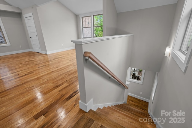 stairs with hardwood / wood-style flooring and vaulted ceiling