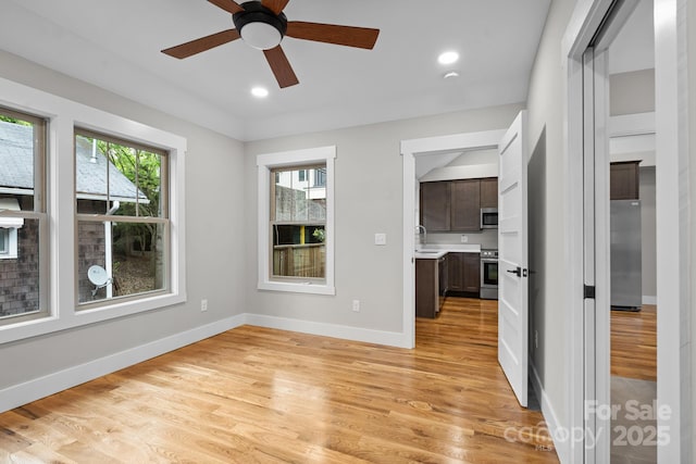 spare room featuring light wood-type flooring, ceiling fan, and sink