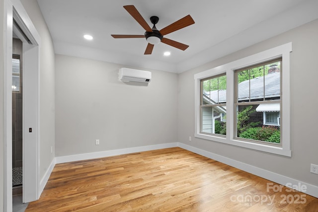 unfurnished room featuring ceiling fan, a wall mounted AC, and light wood-type flooring