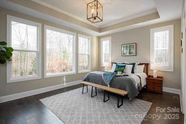 bedroom featuring dark hardwood / wood-style flooring, a notable chandelier, a tray ceiling, and ornamental molding