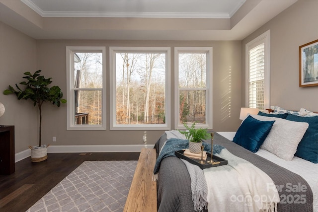 bedroom with a raised ceiling, crown molding, and dark wood-type flooring