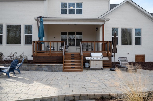 back of house with a wooden deck and a patio