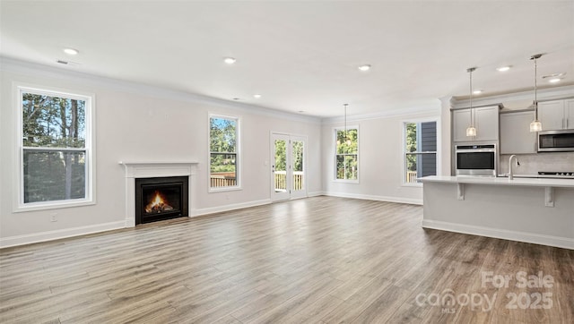 unfurnished living room with ornamental molding, hardwood / wood-style floors, and sink